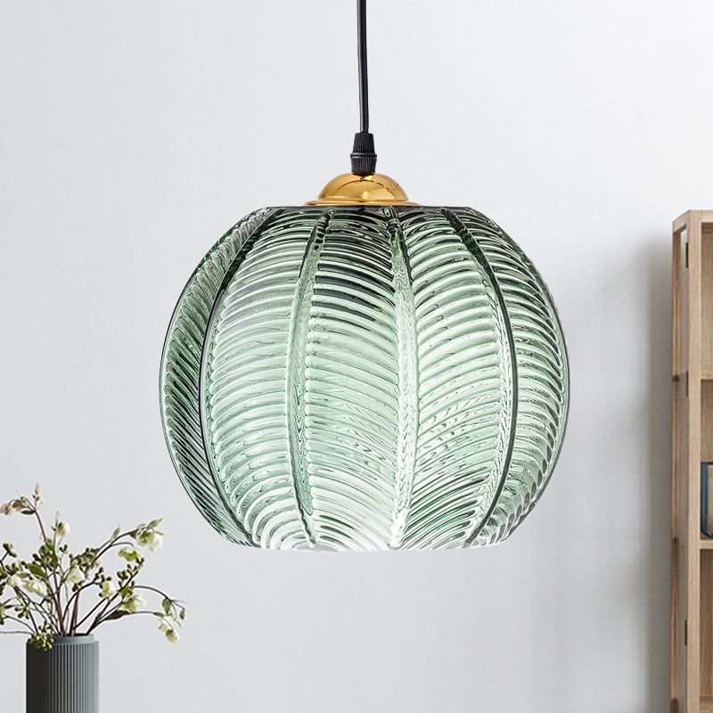 Green ribbed pendant lit beside a shelf, showing its curved glass texture.