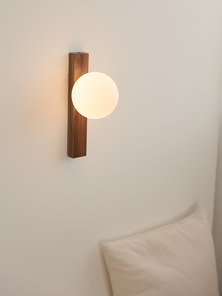 Illuminated Lunaria walnut wall lamp above upholstered furniture