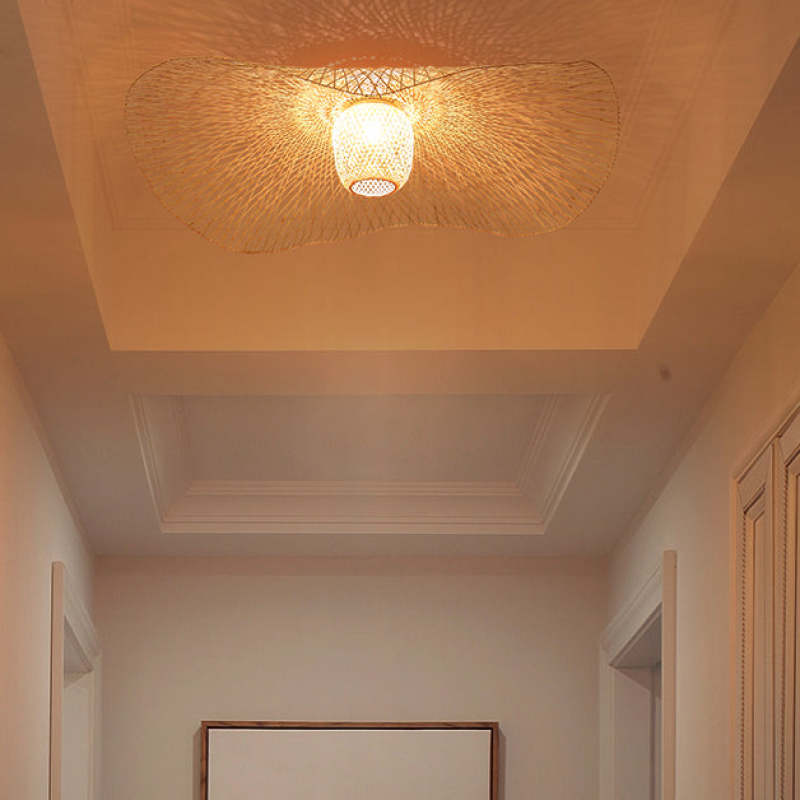 View from below of a lit wavy woven pendant in a recessed ceiling above a framed mirror