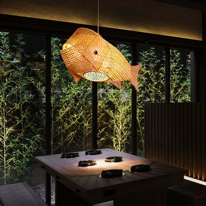Illuminated Muto fish pendant above a dining table near a garden-facing window