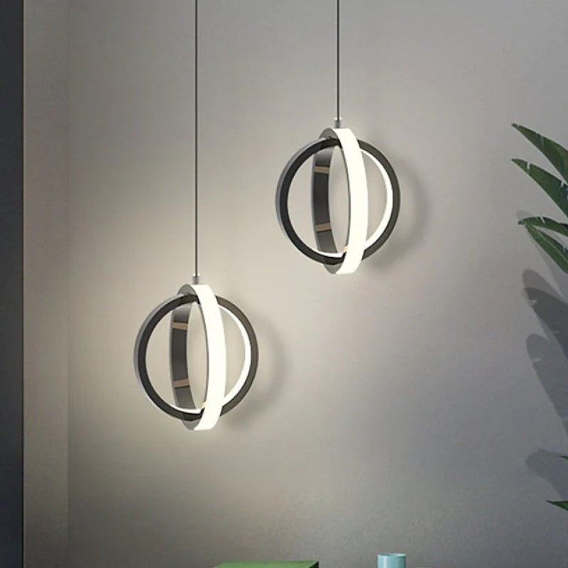 Two illuminated black Lynch spherical ring pendants against a grey wall.