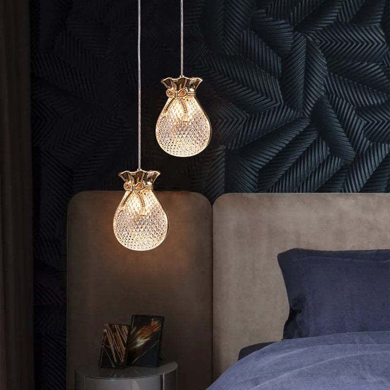 Two glowing pouch-shaped Hailie lights beside a dark upholstered bed.
