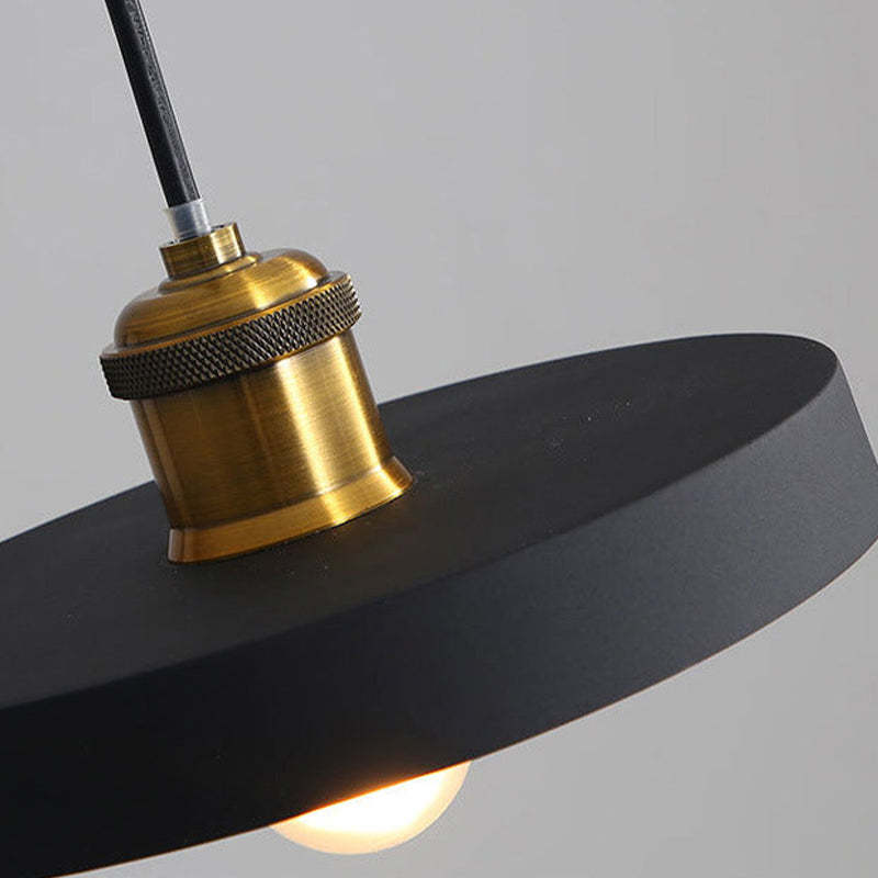 Close view of a Morandi black disc shade, gold-coloured fitting and exposed bulb.