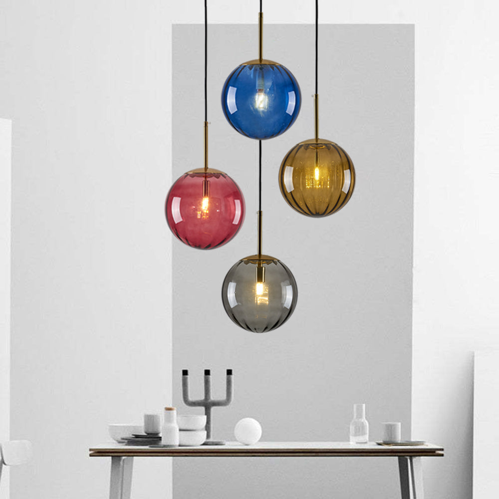 Four tinted glass globes above a console with White bowls, bottles and Black candelabra against a White and Gray wall