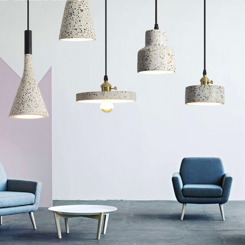 Five speckled pendants above blue lounge chairs and a white coffee table in a pastel room