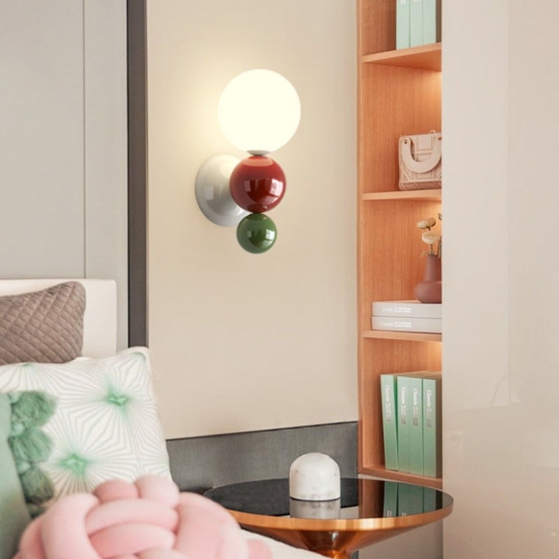 Green-accent Valentina wall light beside a bed and shelving