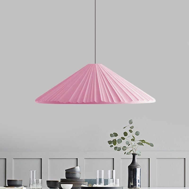 Pink shallow pleated cone pendant above a dining table with glasses, bowls and a black vase