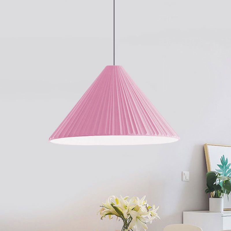 Pink taller pleated cone pendant above lilies near a white cabinet and green artwork