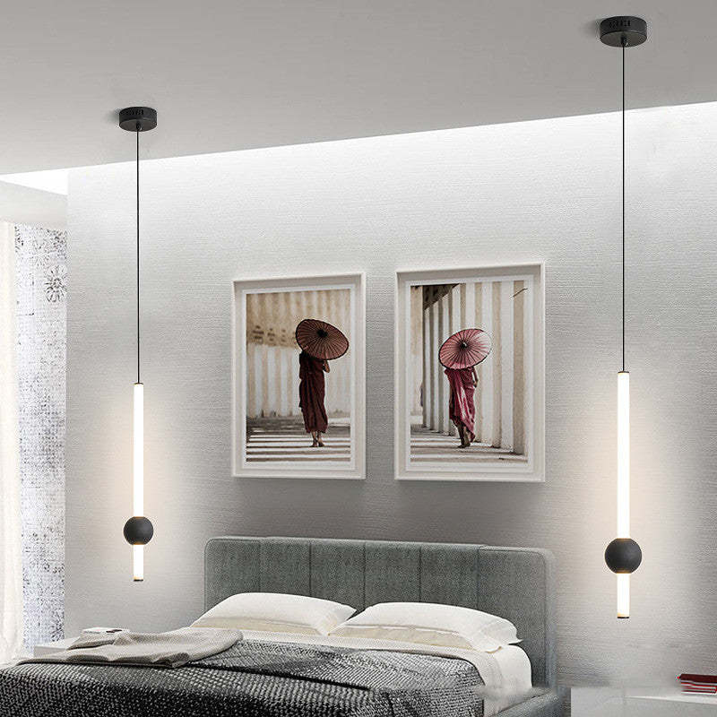 Two white-rod Carr pendants with dark globes beside a bed.