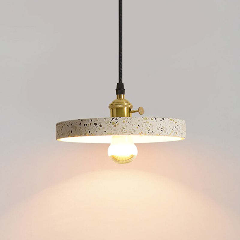 Flat speckled disc pendant with a visible glowing bulb below and gold-tone holder above