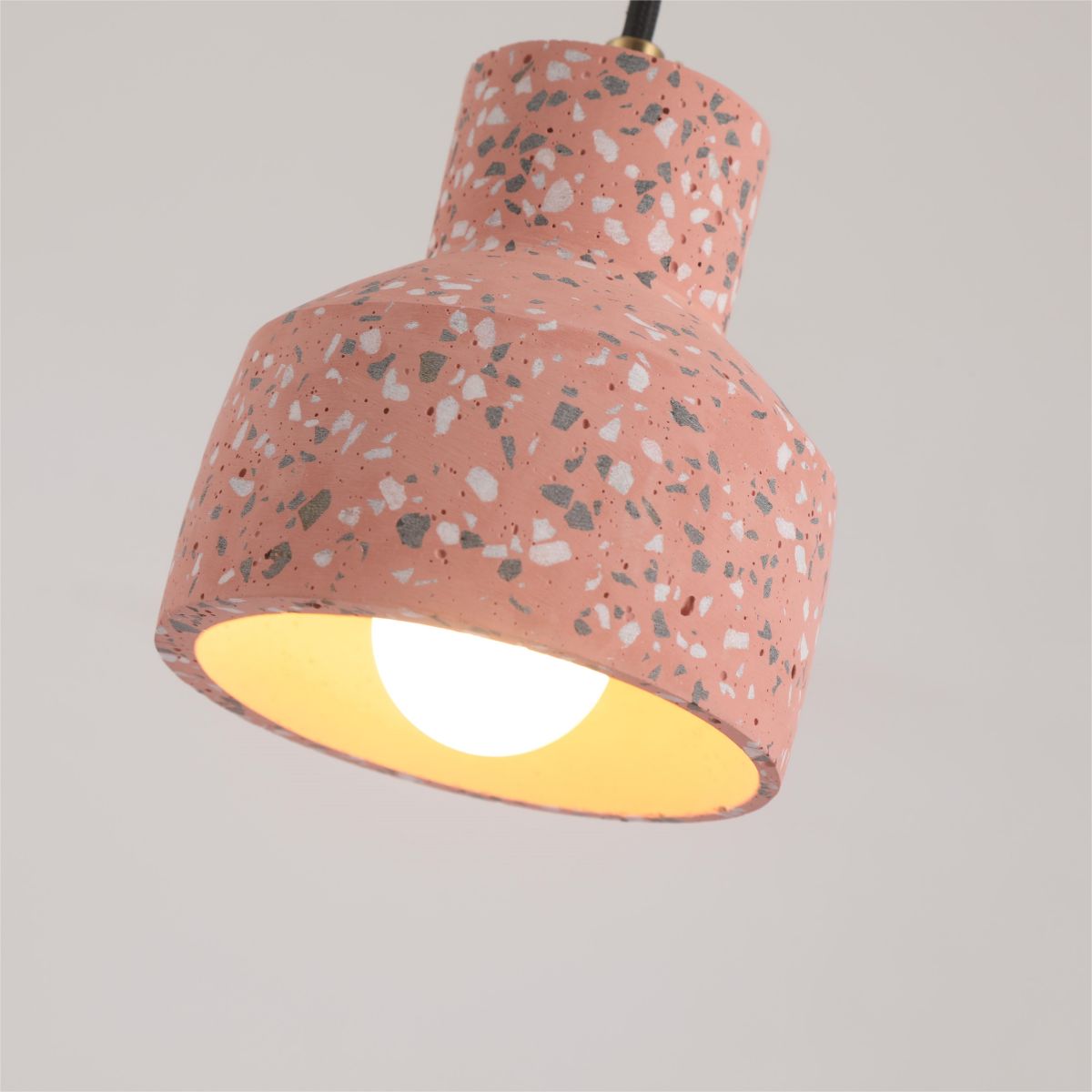 Low-angle Red Morandi cement shade closeup with a lit bulb and warm yellowish glow inside the coral-toned shade