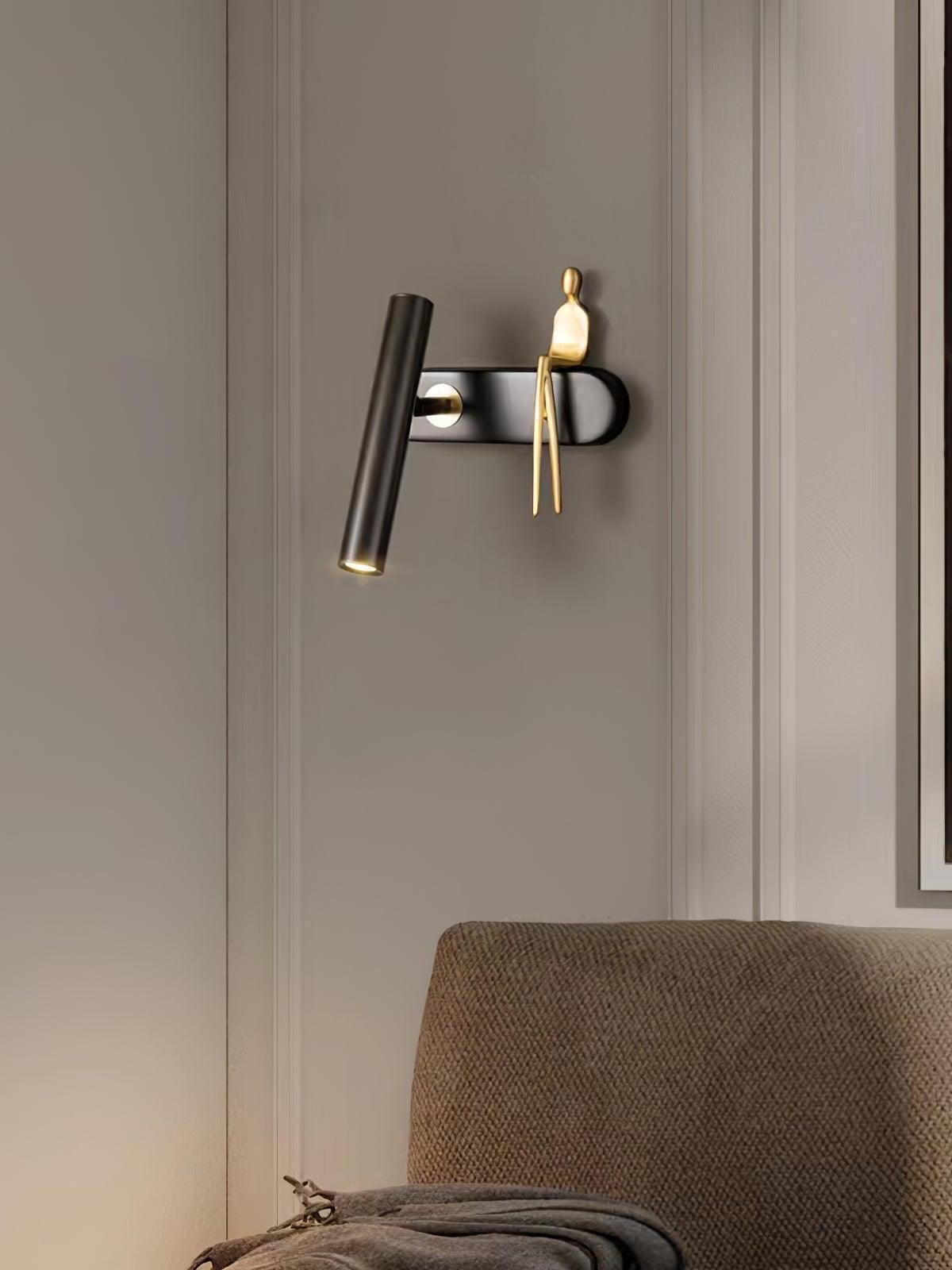 Black tube and gold seated figure mounted above a bedhead against a panelled wall