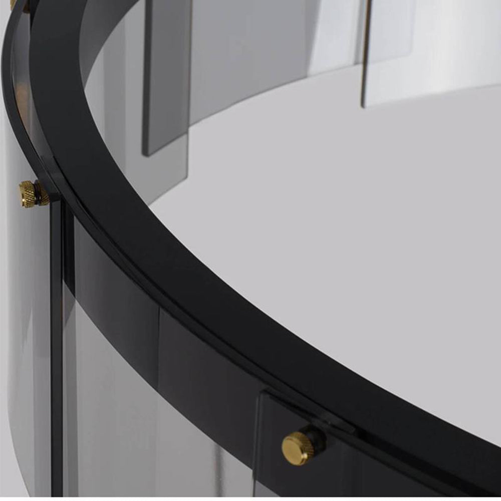 Unlit close-up of the curved black rim, overlapping smoky-looking glass panels and small gold-tone fasteners