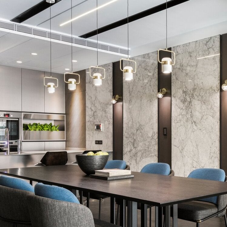 White Cooley framed pendants above a dining table near a stone-patterned wall