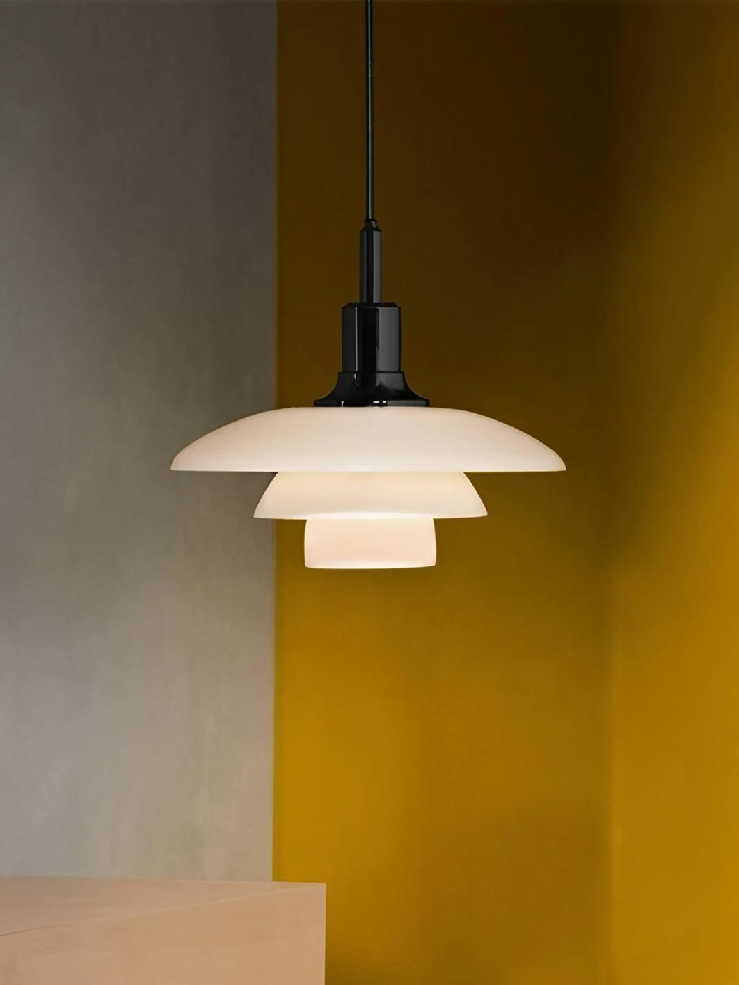 Black-fitted opal disc pendant against a mustard-coloured wall