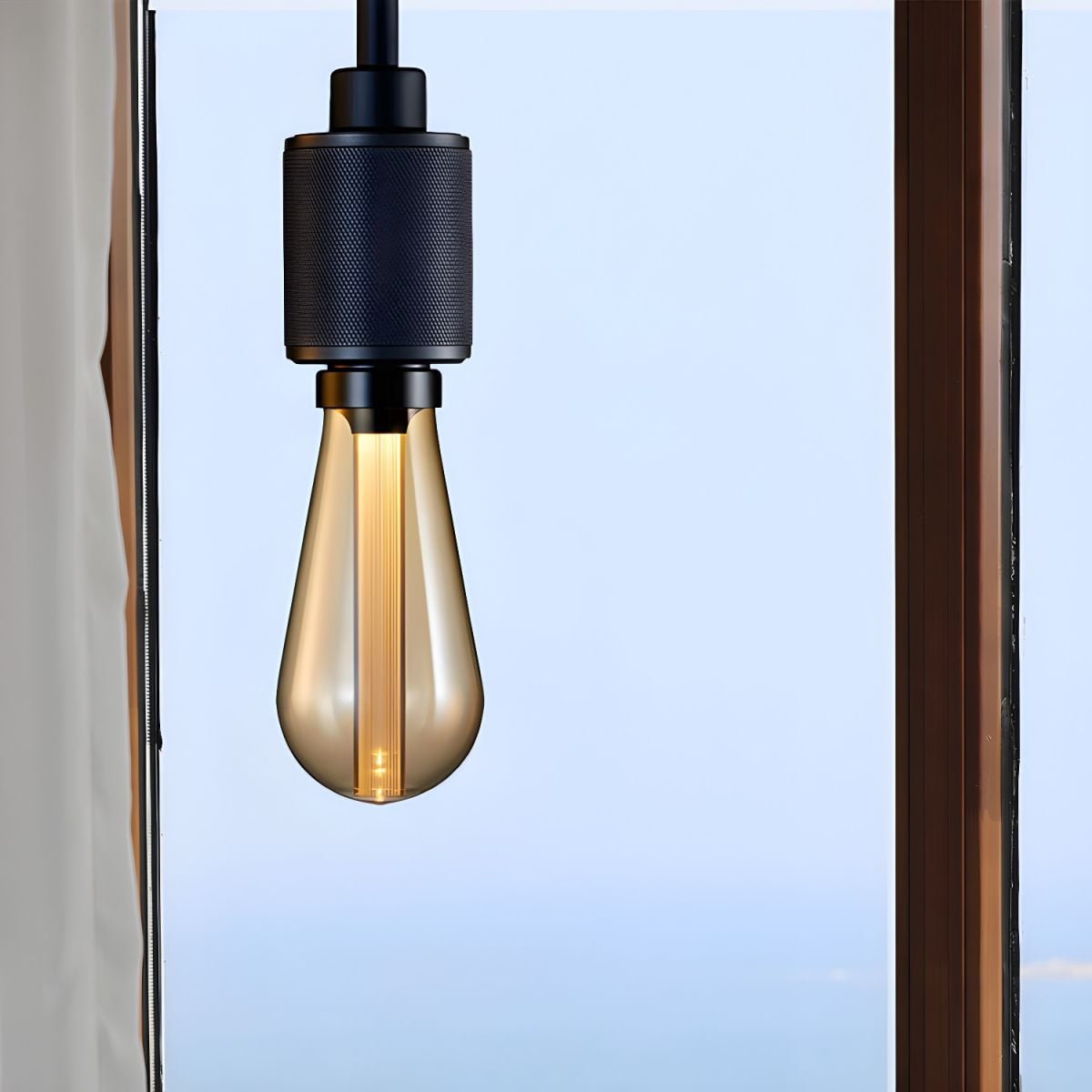 Cooley Black pendant pictured beside a window with a long bulb