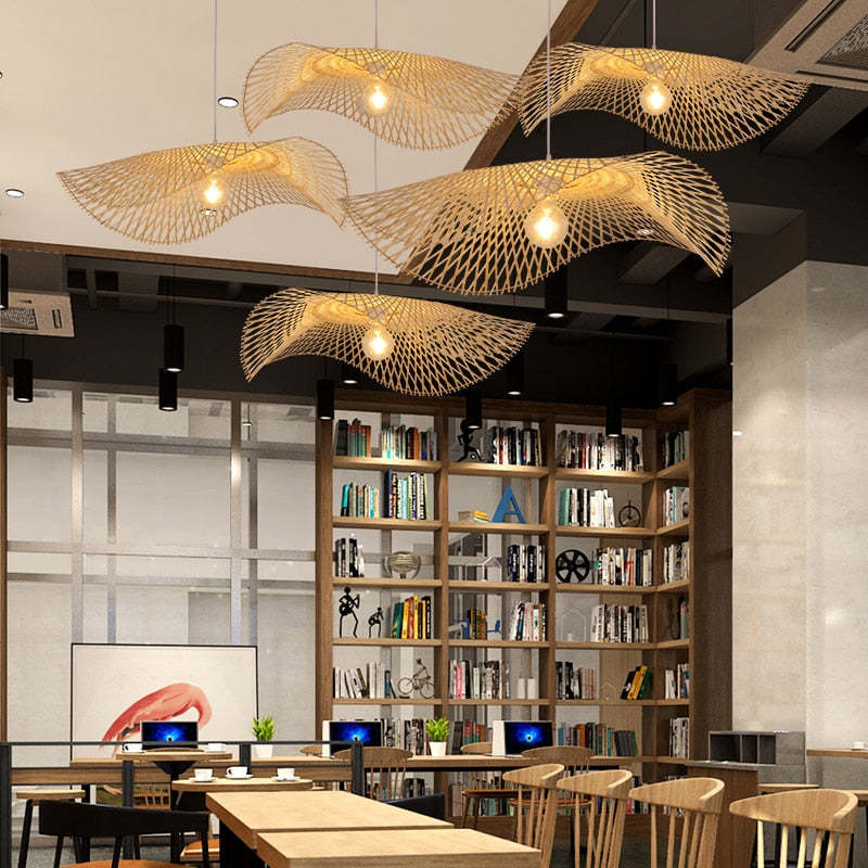 Five wavy woven pendants with visible bulbs above wood tables and chairs in front of bookshelves