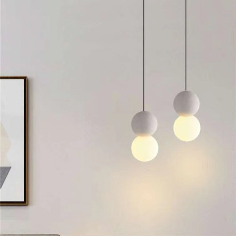 Two pale Byers double-sphere pendants hanging at different heights.