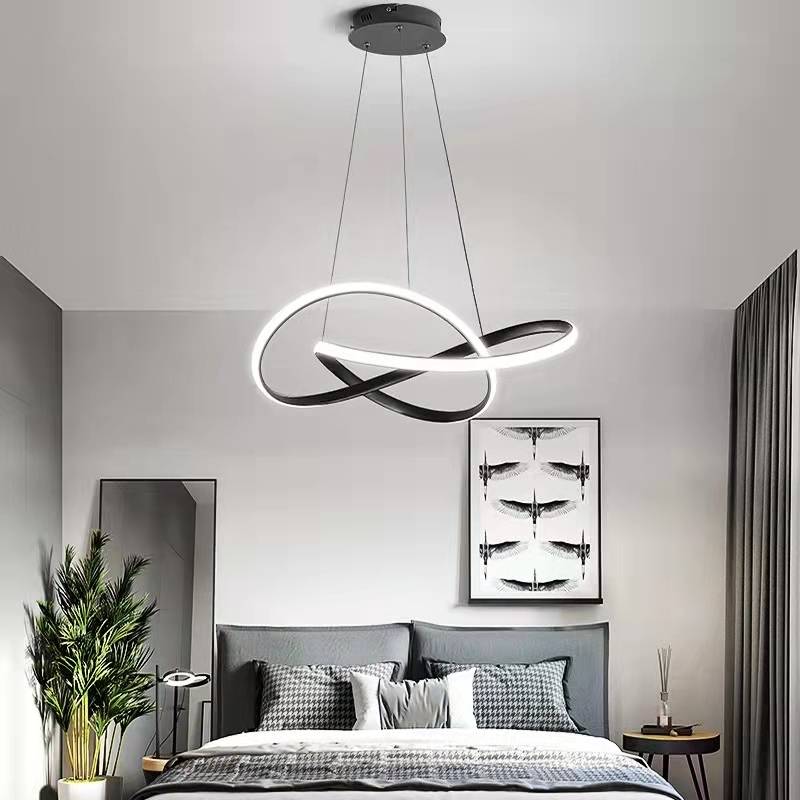 Black Louise illuminated loop pendant above a bed.
