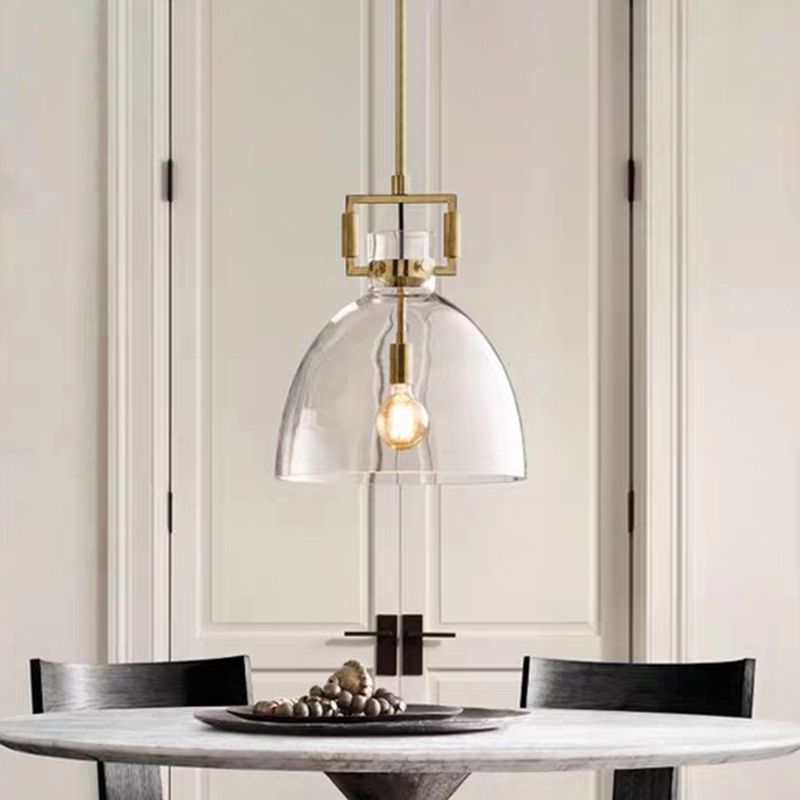 Cairns clear glass dome pendant above a round table with black chairs and a fruit tray