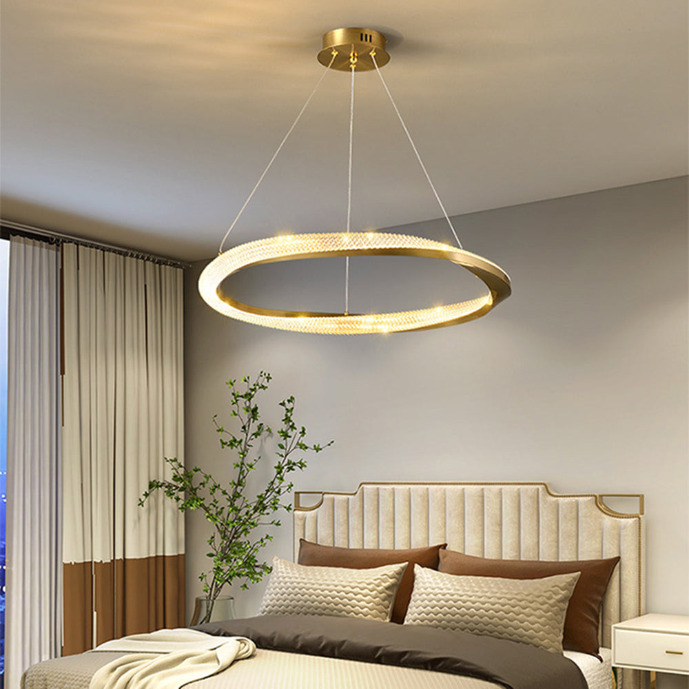 Gold single-ring pendant above a bedroom with a pale upholstered headboard and curtains