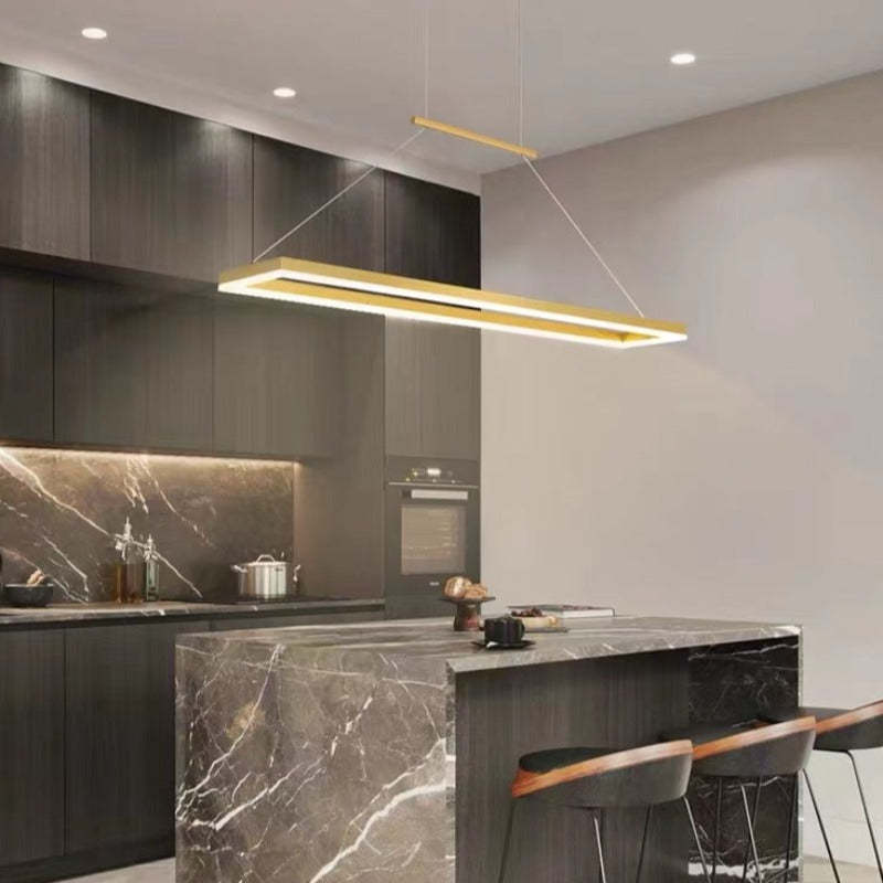 Gold rectangular pendant over a marble-look kitchen island beside dark cabinetry and an oven