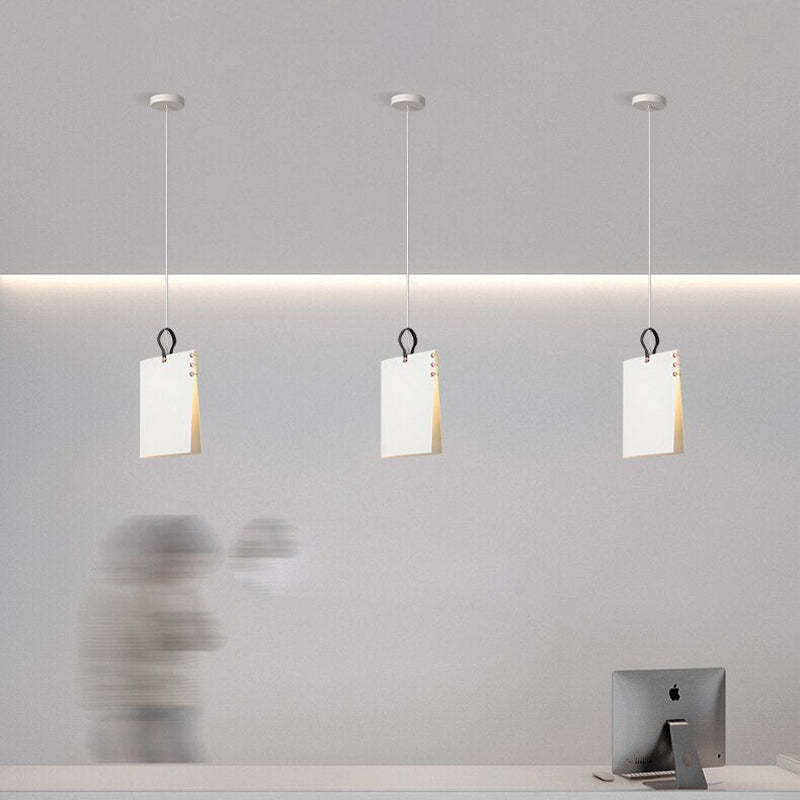 Three separate White Sienna upright panel pendants with dark loops above a computer desk, with a blurred person nearby