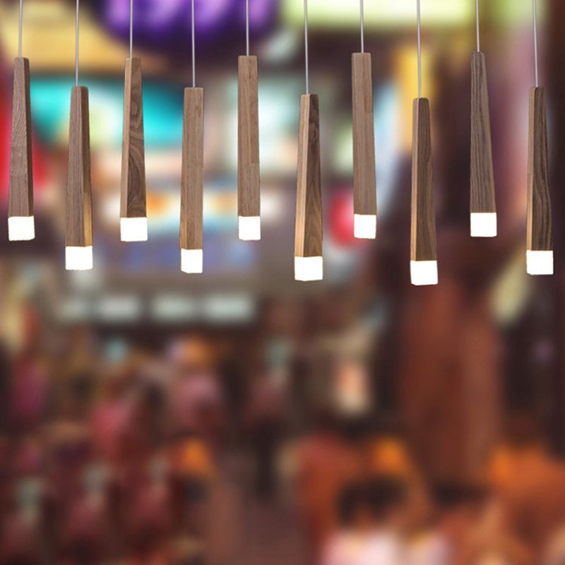 Group of Ozawa wood column pendants with white tips against a blurred colourful café-style background.