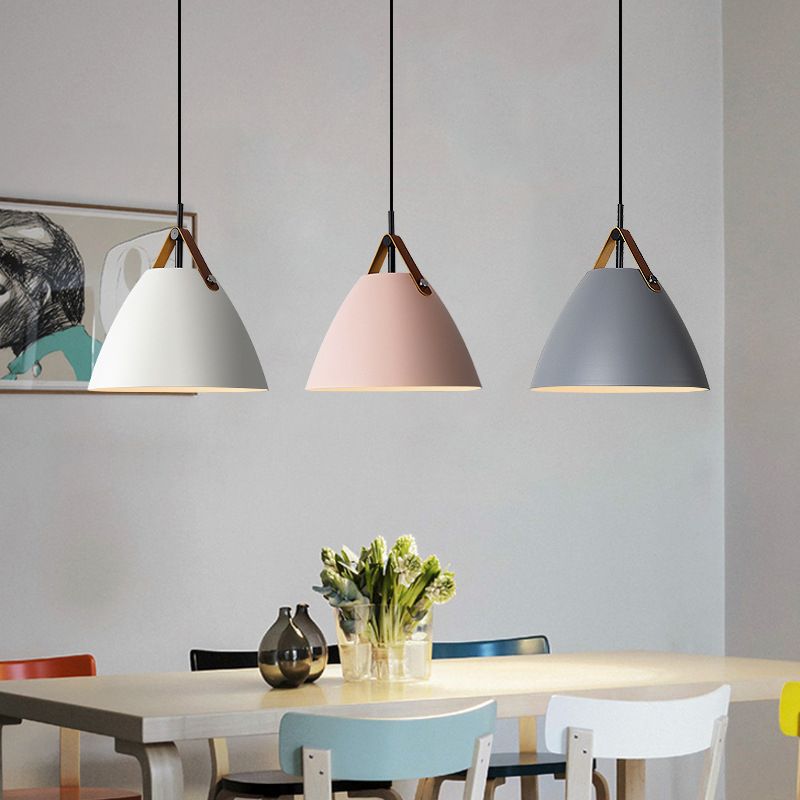 White, pink and gray cone pendants above a dining table with coloured chairs, flowers and framed artwork