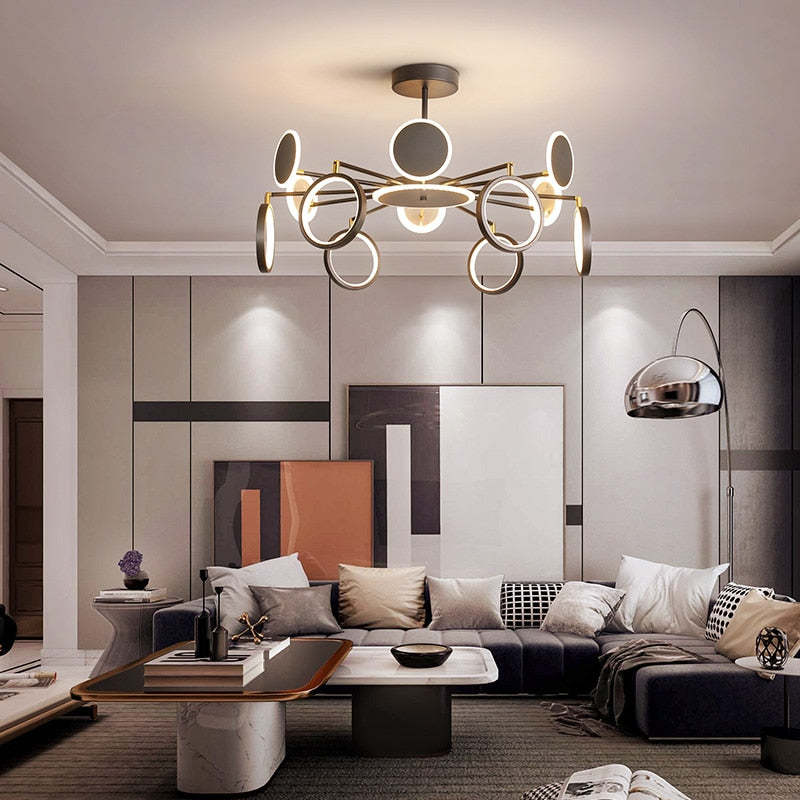 Radial ring and disc chandelier with several heads tilted vertically above grey seating and framed artwork