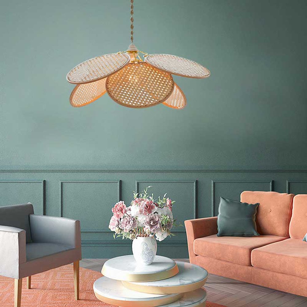 Woven petal pendant above nested white coffee tables with flowers between a gray chair and salmon sofa against a mint wall