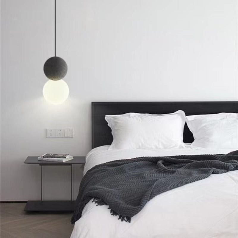 Black Byers two-sphere pendant illuminated beside a bed.