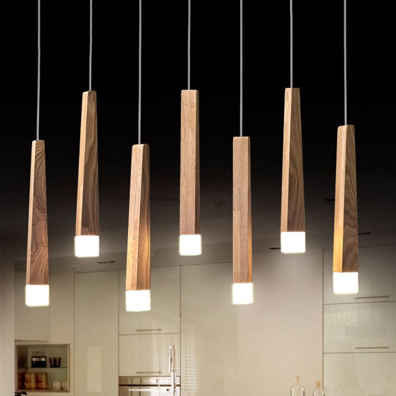 Several Ozawa wood column pendants hanging at staggered heights above a pale kitchen setting.