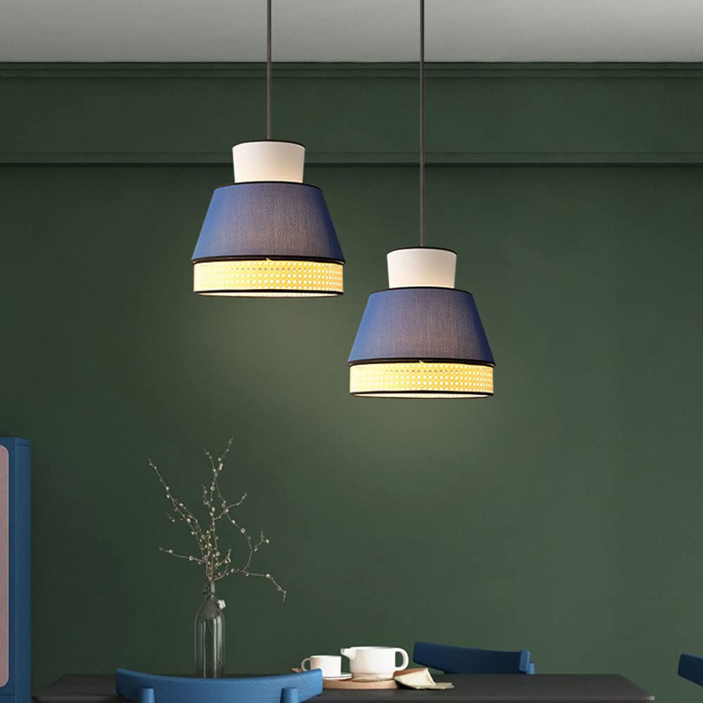 Two blue-and-white Ritta Style B pendants over a dark dining table with a teapot, blue chairs and green wall panels.