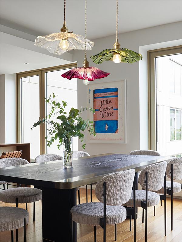 Clear, green and purple lotus pendants grouped above a dining table