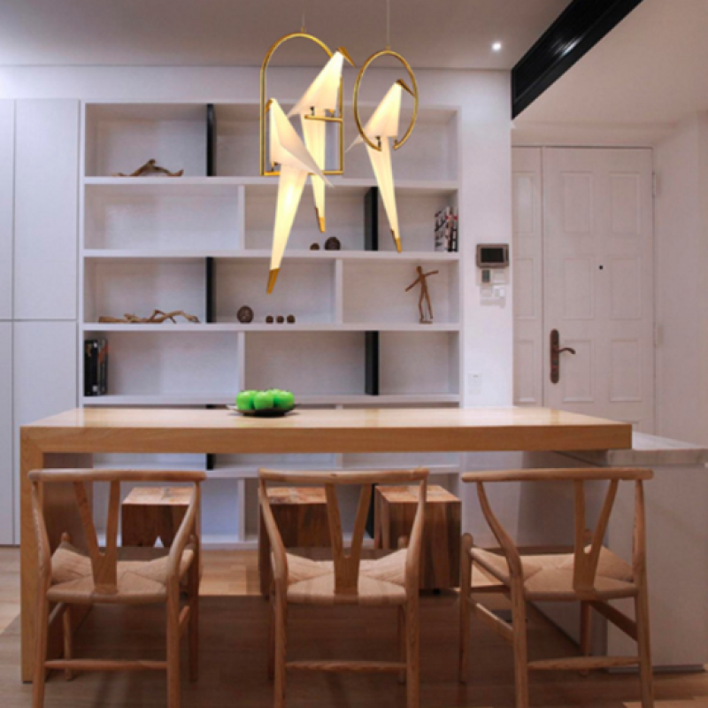 Several bird pendants above a wooden dining table in a furnished room.