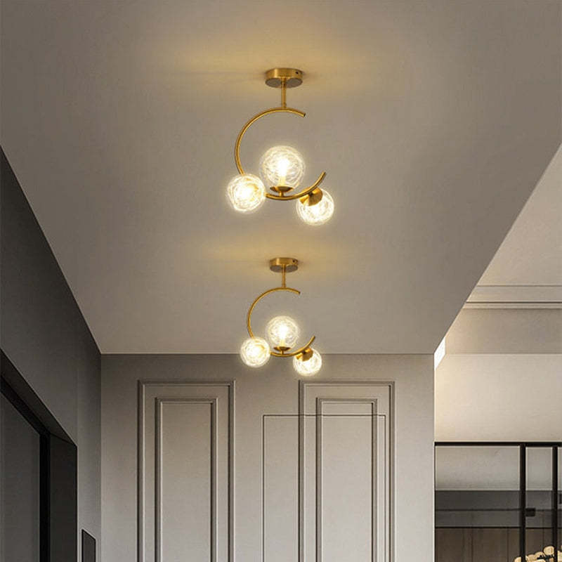 Two three-globe clear ceiling fixtures with glowing strand detail along a hallway