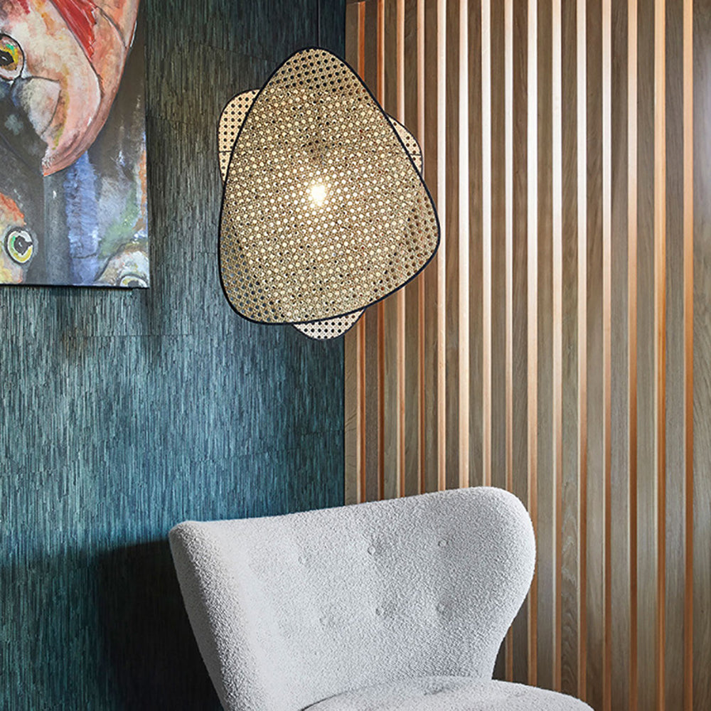 Ritta woven pendant above a grey chair beside a timber-slatted wall.