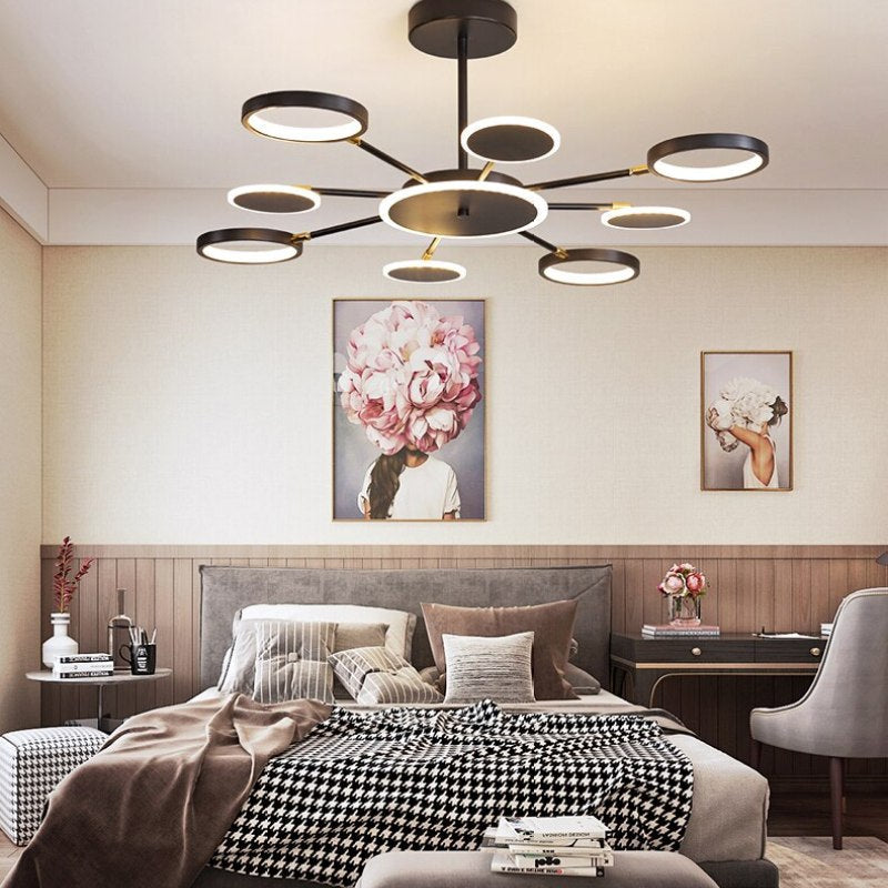 Eight-arm ring and disc chandelier above a bed with floral portraits and a houndstooth blanket
