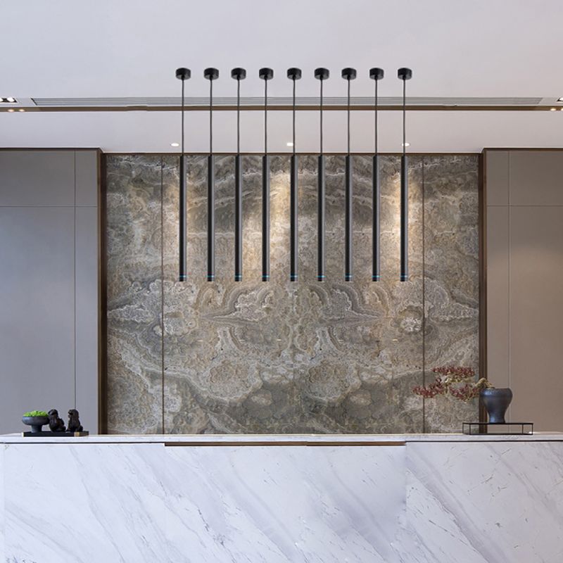 Row of black Edge cylinder pendants above a stone counter with a patterned stone wall behind