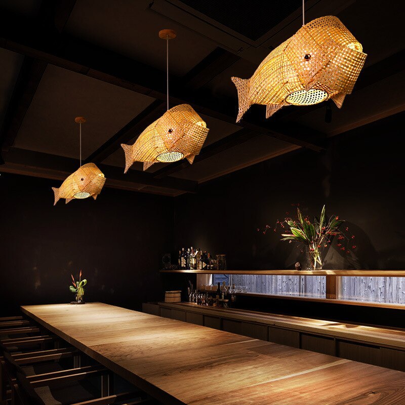 Three Muto fish lights hanging over a long wooden restaurant counter