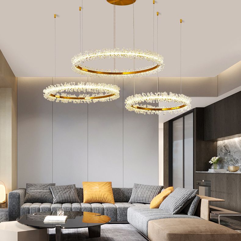 Three illuminated Kristy flower rings at staggered heights above a grey sectional sofa with yellow cushions.