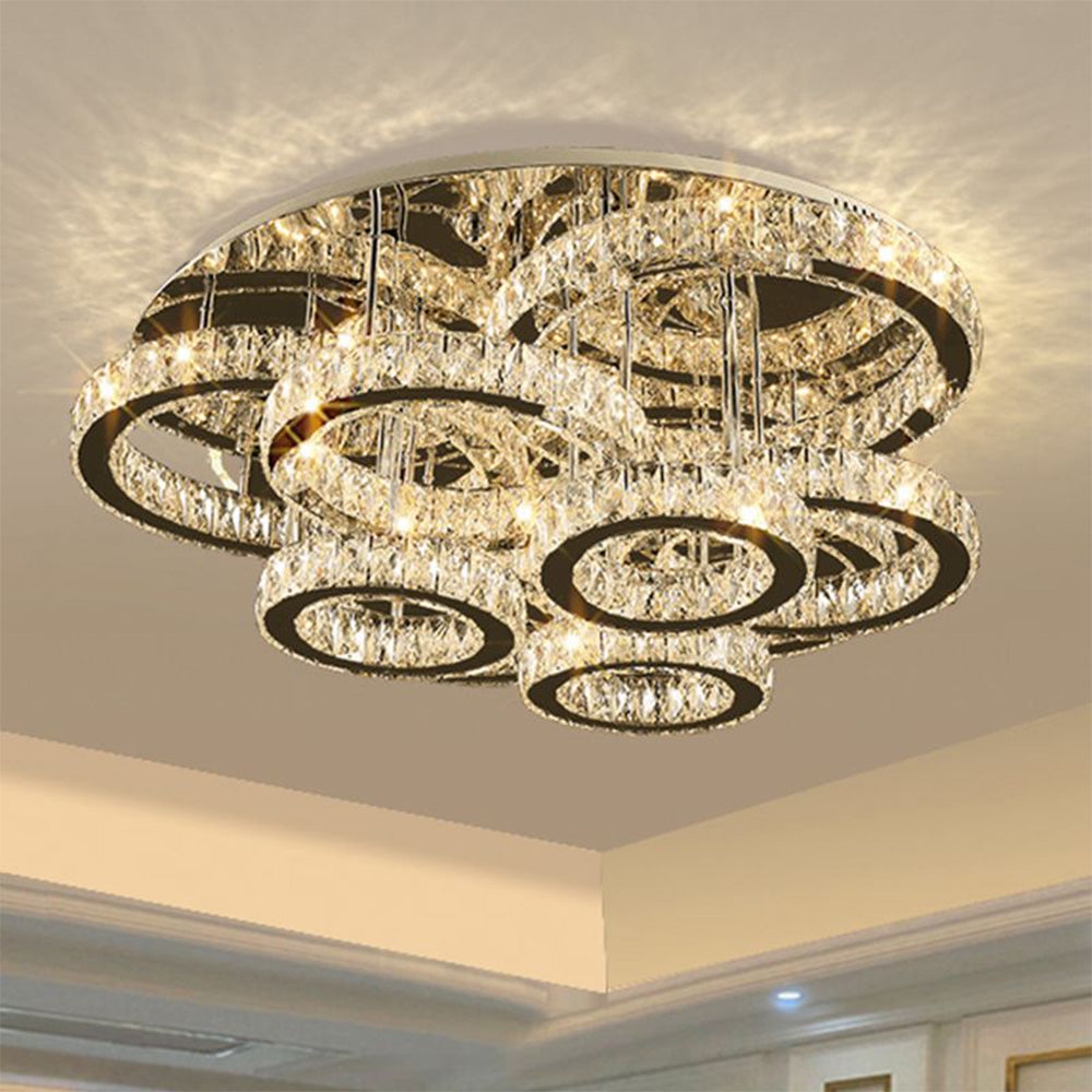 Close view of lit crystal ring tiers and supporting rods beneath the circular ceiling plate.