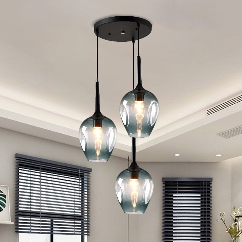 Blue-tinted glass cluster pendant with three shades near windows with dark blinds