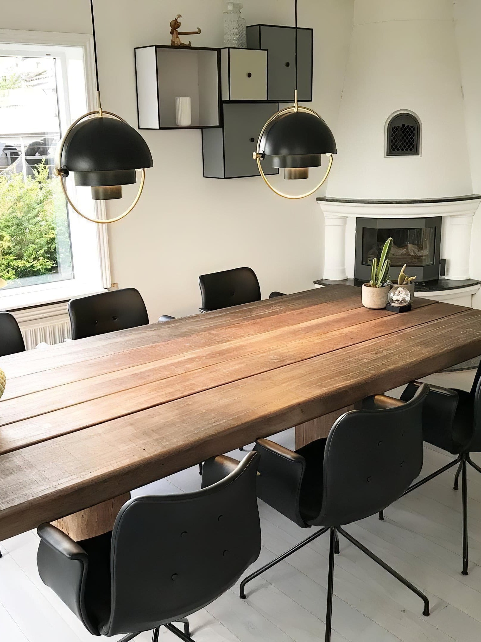 Black dome pendants over a long wooden dining table
