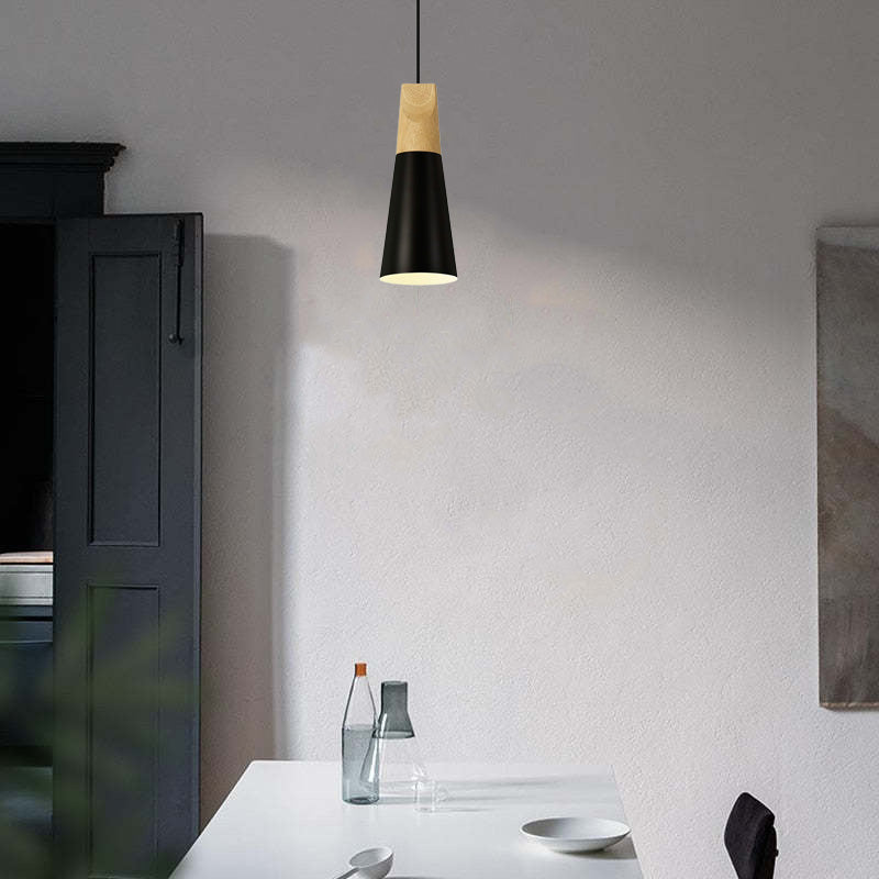 Black narrow pendant above a white table with glass bottles beside a dark cupboard