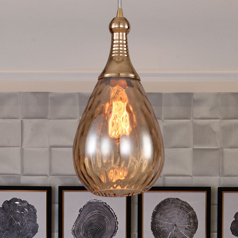 Avi Brass-Amber textured glass pendant above framed artwork