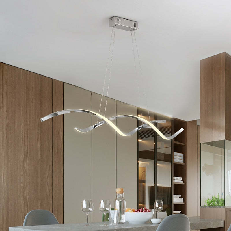 Chrome Louise wavy pendant above a dining table beside wooden cabinets
