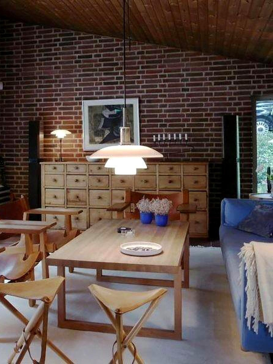 Opal disc pendant above a dining table in a brick-walled room
