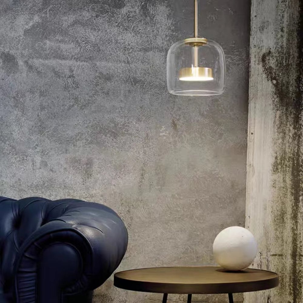Compact Clear Hailie pendant beside a dark armchair and round table